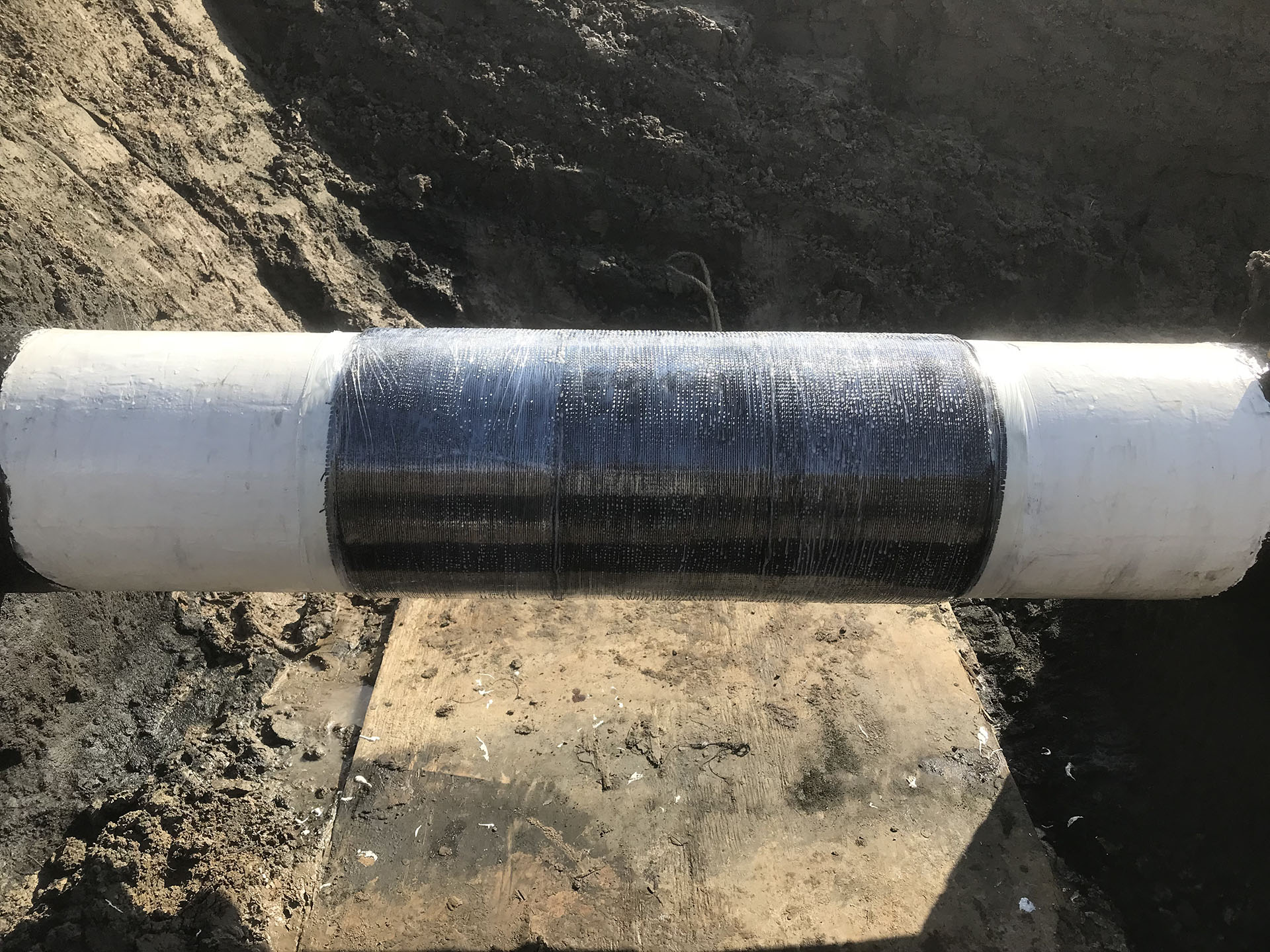 The team installed 24 layers of composite cloth over a 3-ft (1-m) section of pipeline, then covered the repair area with constrictor wrap and perforated it to allow the composite to cure.
